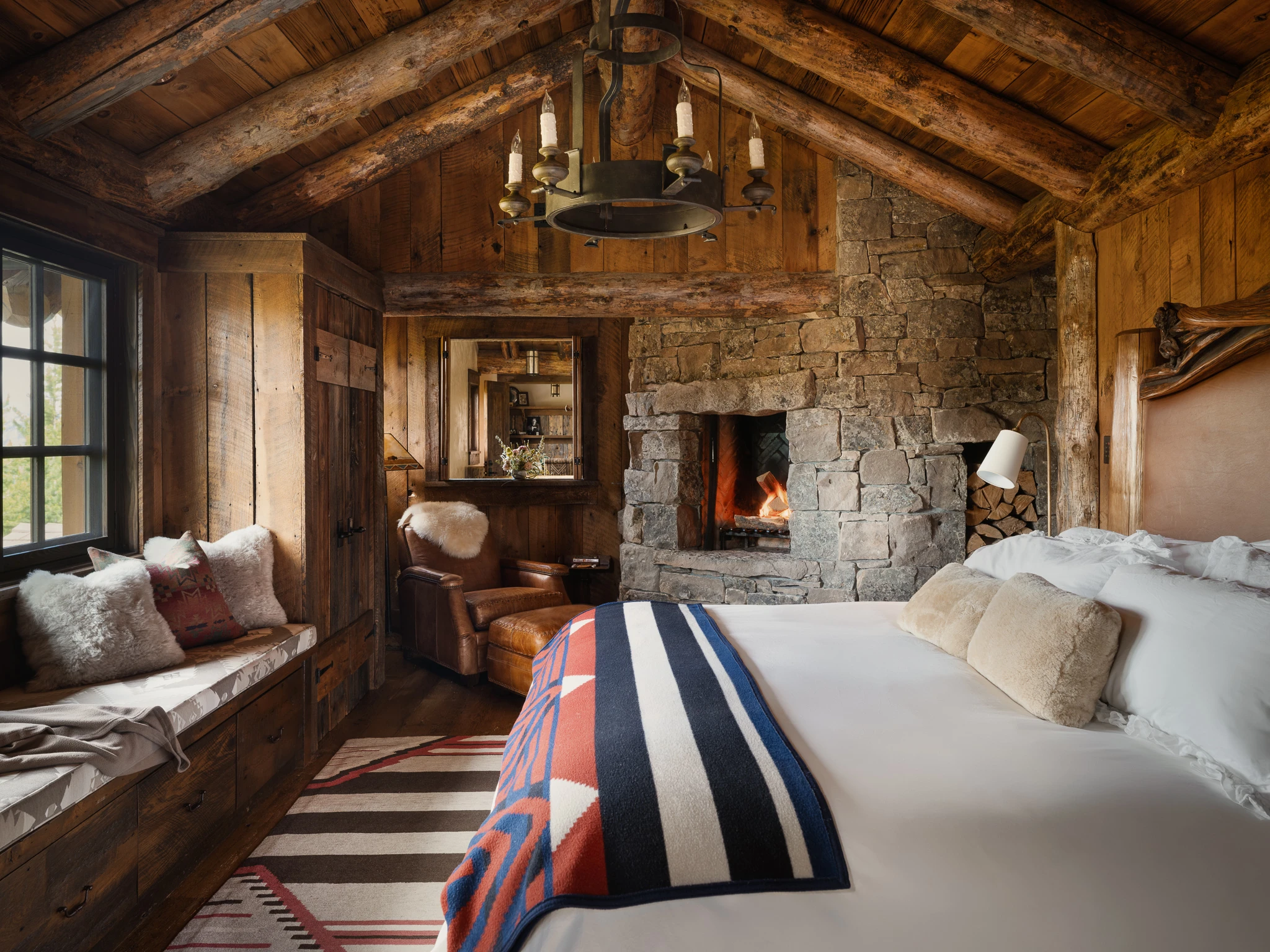 Primary suite with stone fireplace and window seat — interior design photography Big Sky Montana, Club Ridge